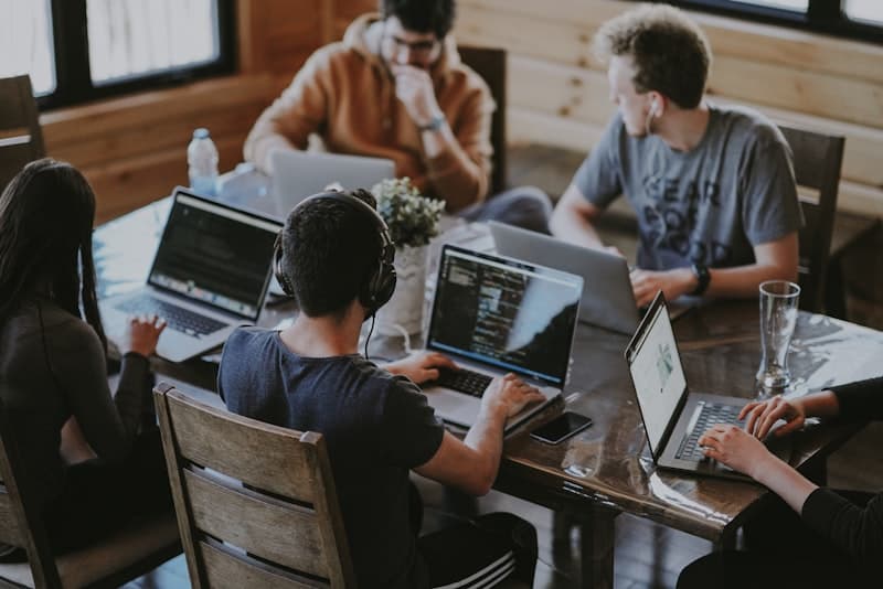 Team collaborating at a table with laptops